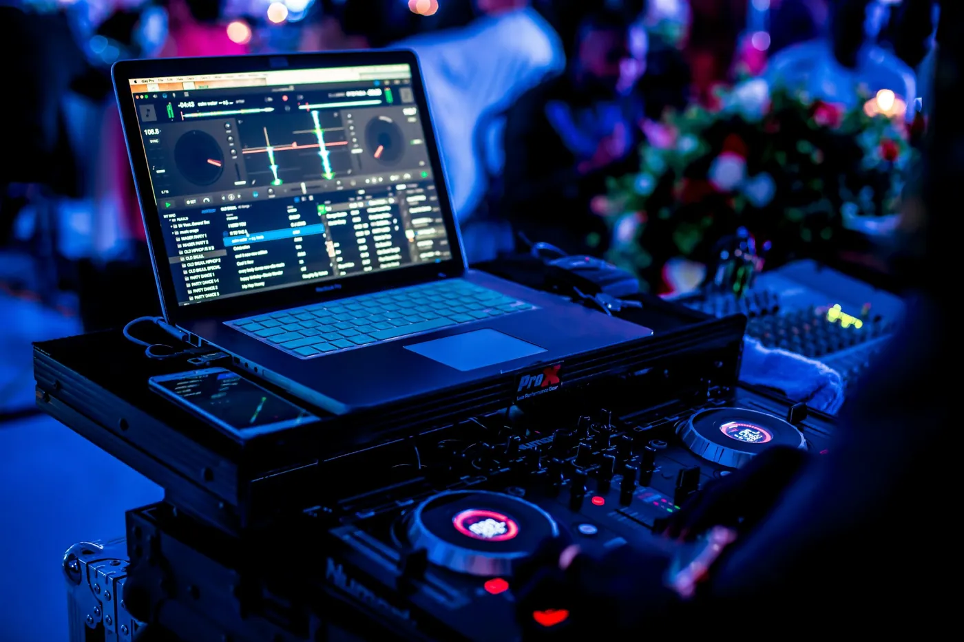 A DJ booth lit in blue at a packed event.